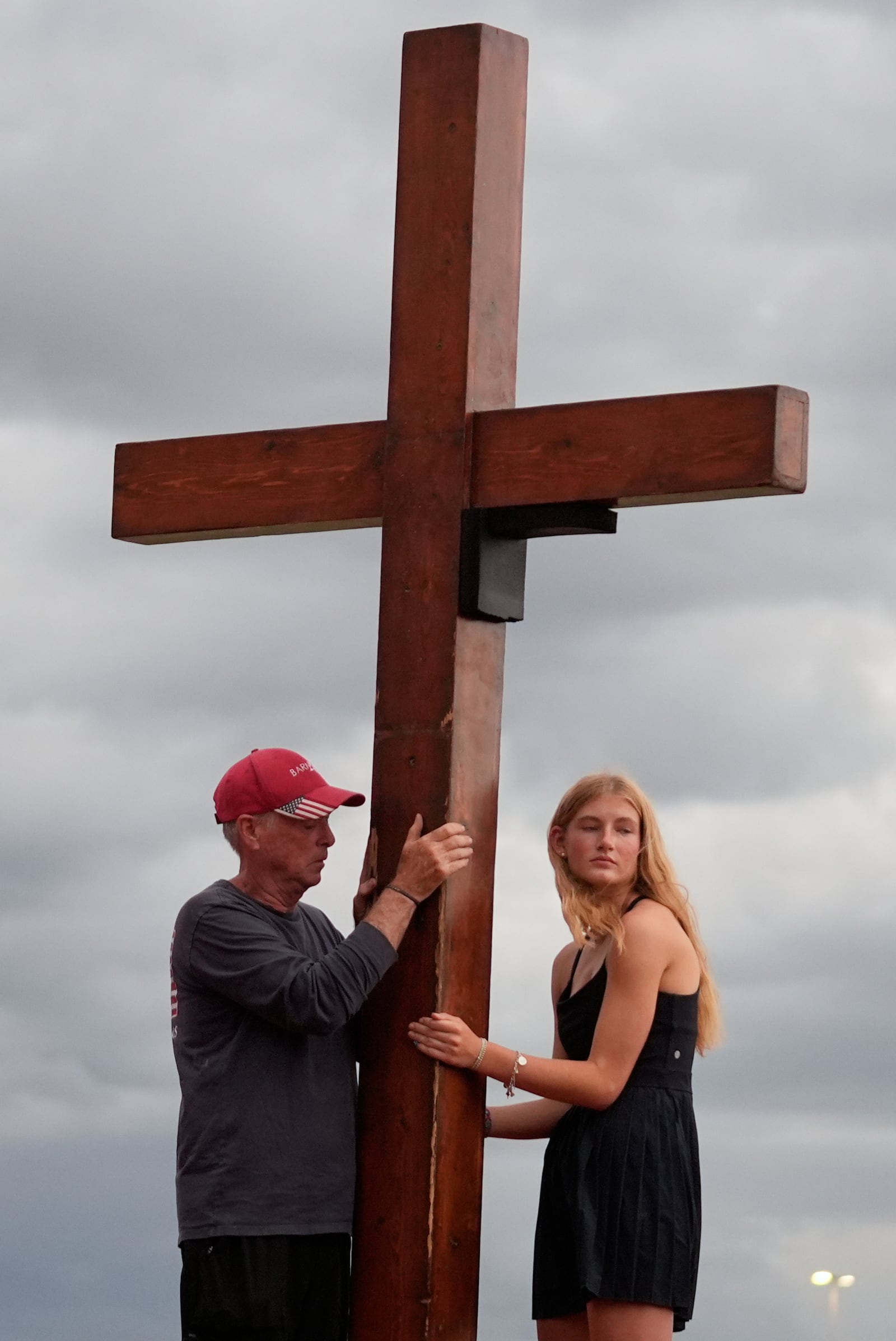 Dan Beazley, of Michigan, left, and Abigail Smithson hold a large cross during a vigil for flooding victims at Tivy Antler Stadium on Wednesday, July 9, 2025, in Kerrville, Texas. (AP Photo/Gerald Herbert)