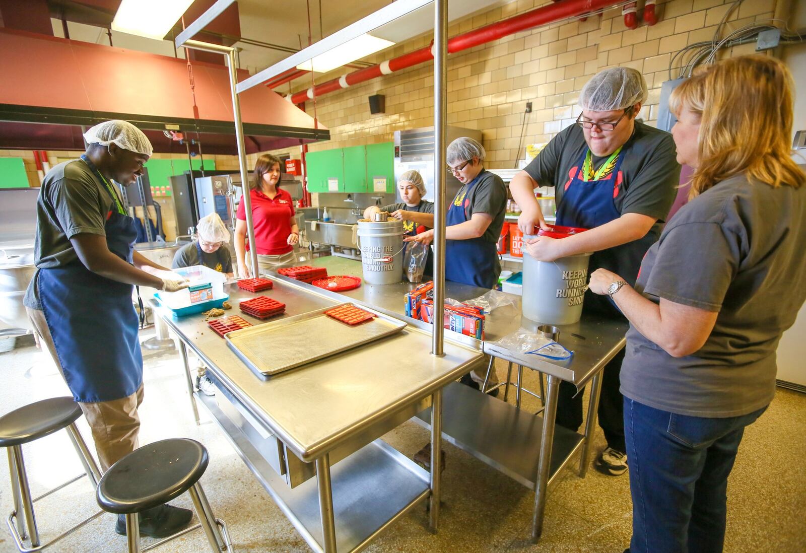 Jill Haenning of Butler Tech and job coach Nancy Michael work with young adults with special needs including Jordan Opoku, Gabby Jones, Eavilee Rainey, Ethan Courtney and Zach Abney as they make dog bones from used beer hops. 