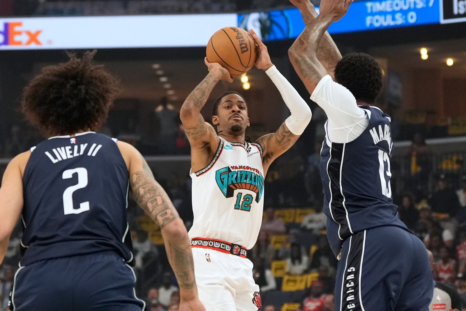 Memphis Grizzlies guard Ja Morant (12) shoots the ball past Dallas Mavericks center Dereck Lively II (2) and forward Naji Marshall, right, during the first half of an NBA play-in tournament basketball game Friday, April 18, 2025, in Memphis, Tenn. (AP Photo/George Walker IV)