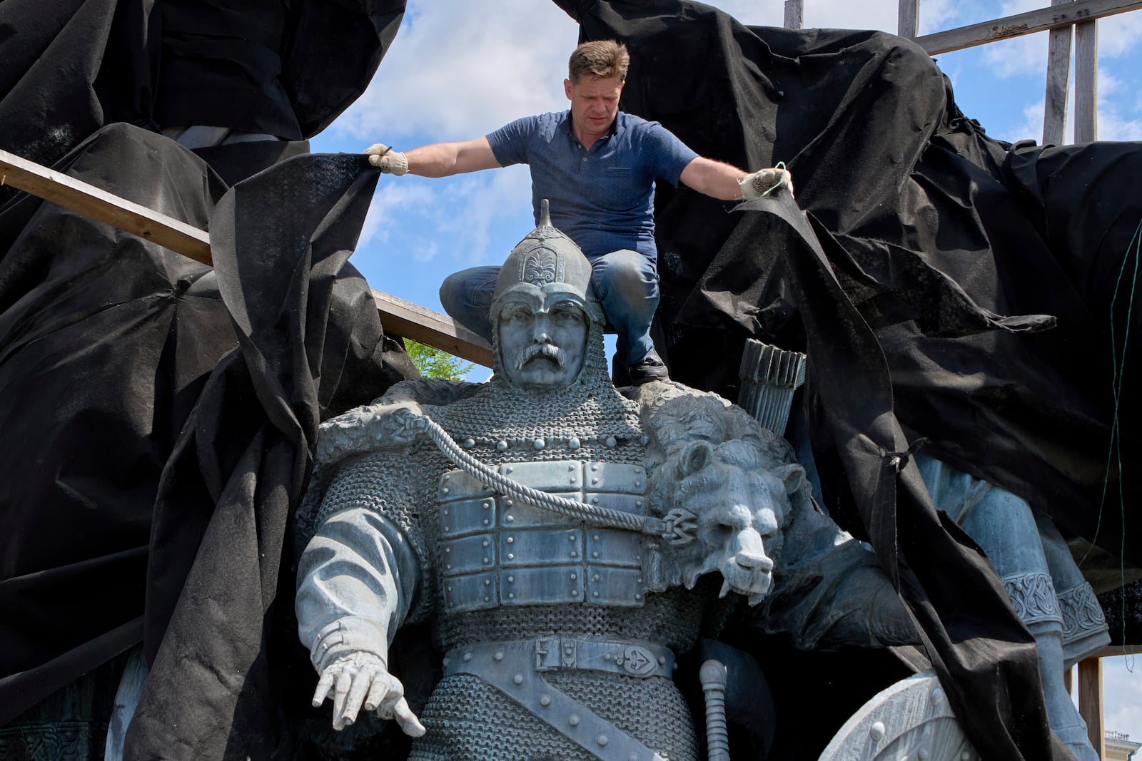 A municipal worker removes the cover that protected a monument to Kyiv legendary founders from Russian missile attacks on the fourth year of Russia-Ukraine war on the country's main square in Kyiv, Ukraine, Wednesday, May 21, 2025. (AP Photo/Efrem Lukatsky)