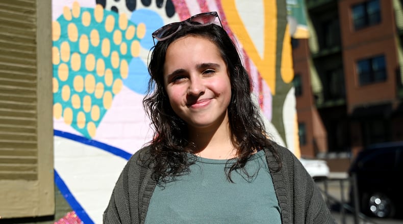 Hannah Baney, a 21-year-old art student at Miami University Hamilton, painted a mural on the east side of True West Coffee on Main Street. This mural, which she offered to do for free, landed her several paying jobs, including in her hometown in Trenton and in Hamilton. Pictured is Baney on Thursday morning, Oct. 23, 2025, in front of her mural. MICHAEL D. PITMAN/STAFF
