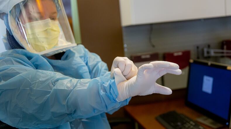 Miami Valley Hospital registered nurse Liz Cozett, dons personal protective equipment, preparing to go into the room of a patient who is positive for COVID-19.