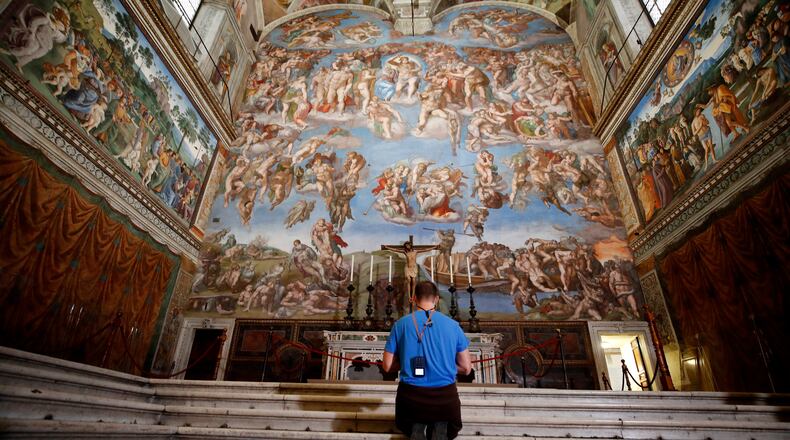 FILE - A visitor kneels in front of the Last Judgement fresco by the Italian Renaissance painter Michelangelo inside the Sistine Chapel in Rome, May 3, 2021. (AP Photo/Alessandra Tarantino, File)