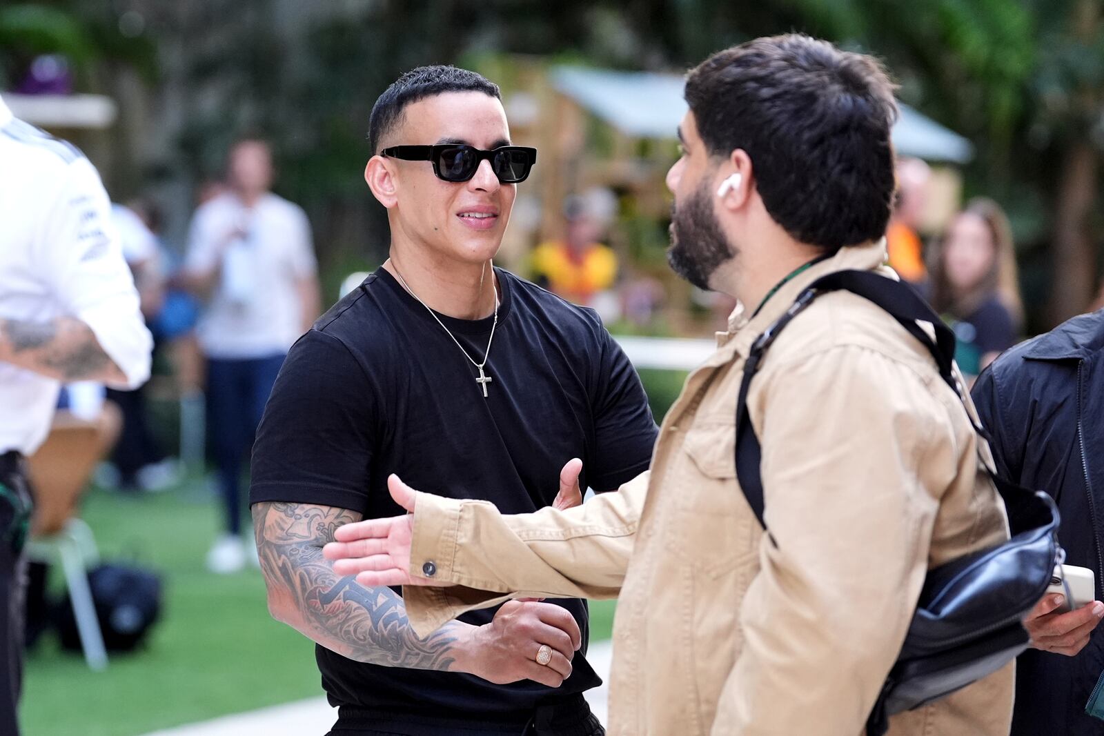 Puerto Rican singer Daddy Yankee, left, speaks with an acquaintance in the paddock area ahead of the Formula One Miami Grand Prix auto race, Thursday, May 1, 2025, in Miami Gardens, Fla. (AP Photo/Rebecca Blackwell)