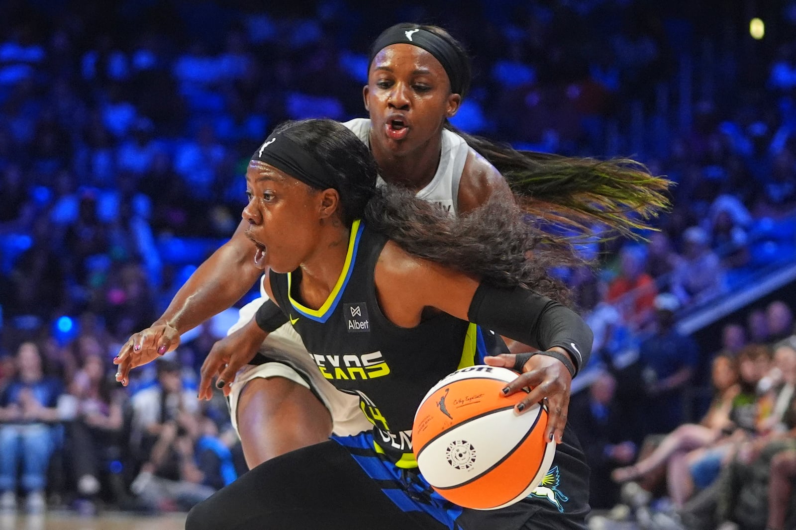 Dallas Wings guard Arike Ogunbowale, front, dribbles against Las Vegas Aces guard Jackie Young, back, during the first half of a WNBA basketball game in Arlington, Texas, Sunday, July 27, 2025. (AP Photo/LM Otero)