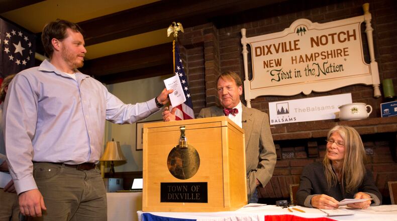 Dixville Notche's first voter Clay Smith drops his ballot into the box as moderator Tom Tillotson watches Tuesday, Nov. 8, 2016, in Dixville Notch, N.H. Democratic candidate Hillary Clinton beat Republican Donald Trump 4-2. (AP Photo/Jim Cole)