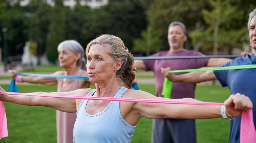 A group of older adults doing arms exercises with colorful resistance bands. ISTOCK