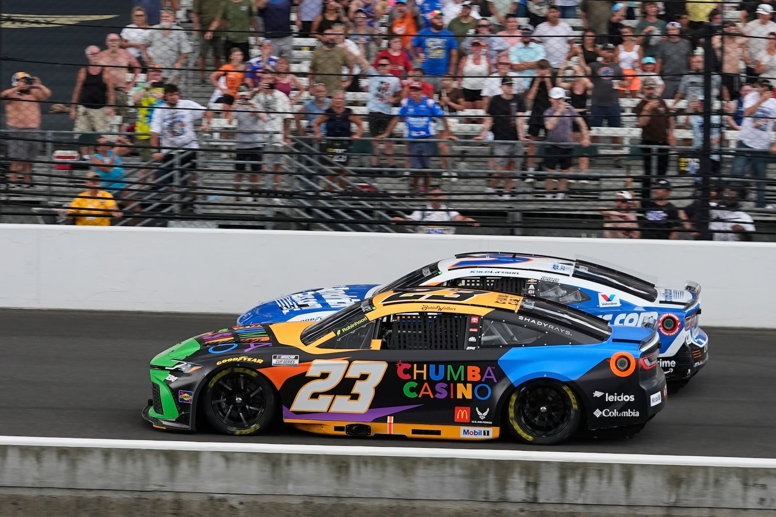 Bubba Wallace (23) leads Kyle Larson restart during a NASCAR Cup Series auto race at Indianapolis Motor Speedway, Sunday, July 27, 2025, in Indianapolis. (AP Photo/Darron Cummings)