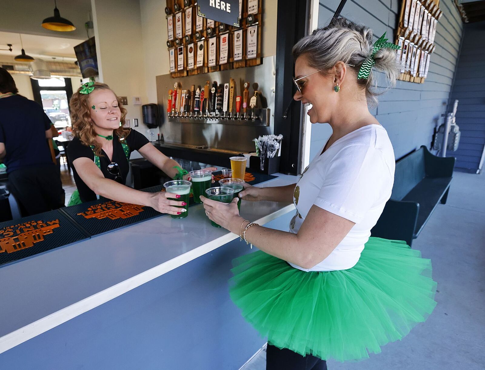 Bartender Brittany Blake, left, serves green drinks to Felicia Weber on St. Patrick's Day Thursday, March 17, 2022 at Hamilton’s Urban Backyard on Main Street in Hamilton. NICK GRAHAM/STAFF