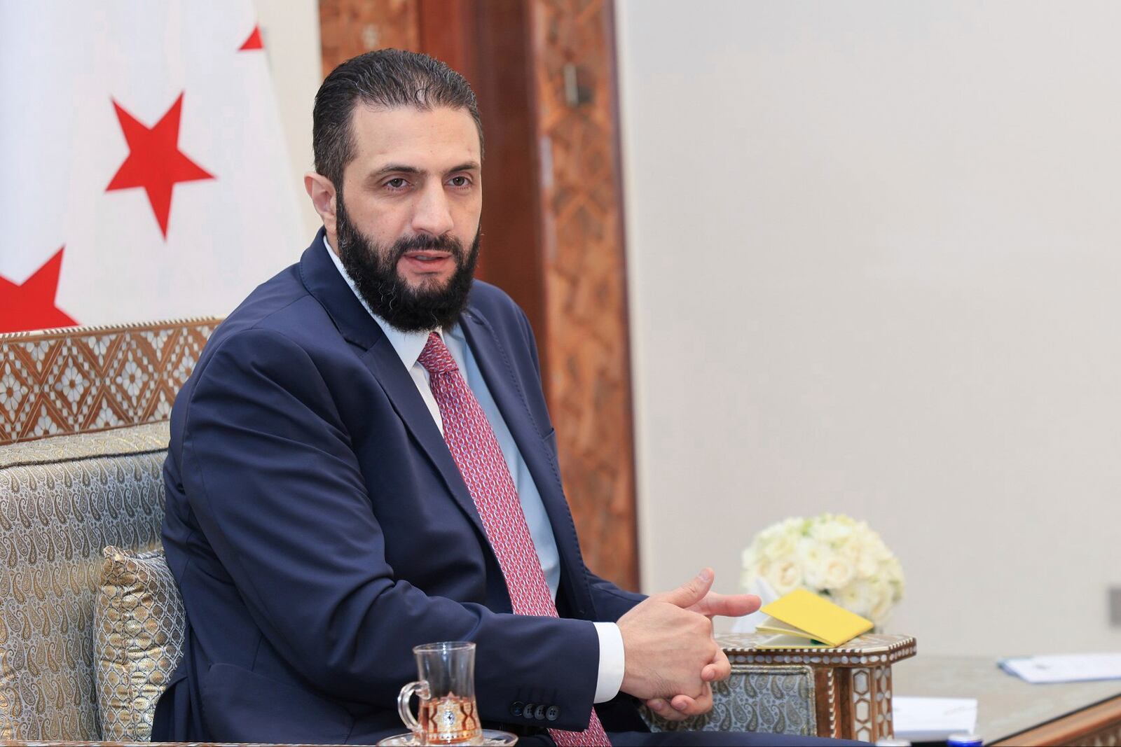 In this photo released by the Syrian official news agency SANA, Syria's interim President Ahmad al-Sharaa receives the final version of the provisional electoral system for the People's Assembly, in Damascus, Syria, Sunday, July 27, 2025. (SANA via AP)