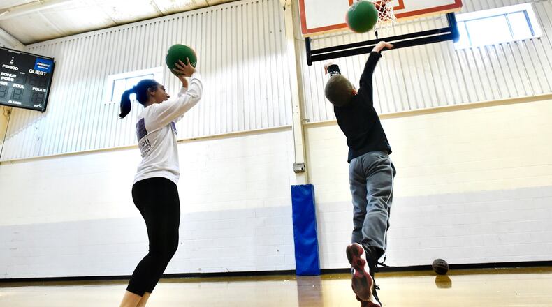 Childcare team member Mckenzie Losekamp plays basketball with a child at Lakota Family YMCA on the final day of of regular state licensed childcare Wednesday, March 25, 2020 in Liberty Twp. Lakota Family YMCA is one of 31 approved facilities with a  Temporary Pandemic Child Care  license in Butler County. Anyone who comes into the YMCA doors must have their temperature taken and parents cannot go past a table set up in the main entrance lobby. NICK GRAHAM/STAFF