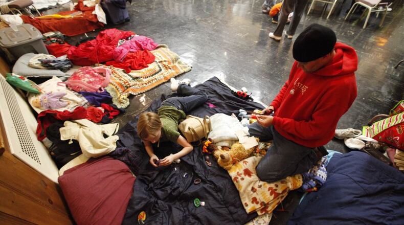 In this 2012 file photo, a homeless veteran and his daughter prepare to sleep on mats inside the SHALOM (Serving the Homeless with Alternate Lodging Of Middletown) shelter at the First Presbyterian Church in Middletown. STAFF/2012
