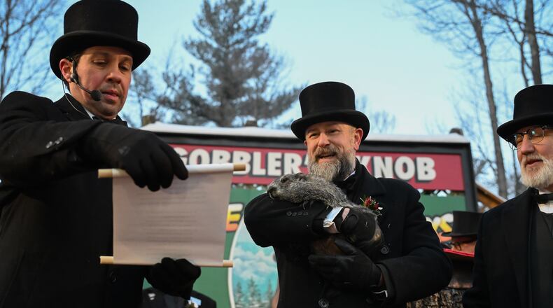 Groundhog Club Vice President Dan McGinley reads the scroll as handler A.J. Dereume holds Punxsutawney Phil, the weather prognosticating groundhog, during the 140th celebration of Groundhog Day on Gobbler's Knob in Punxsutawney, Pa., Monday, Feb. 2, 2026, Phil's handlers said that the groundhog has forecast six more weeks of winter. (AP Photo/Barry Reeger)