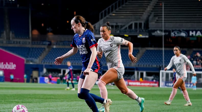 OL Reign midfielder Rose Lavelle, left, moves the ball against Angel City FC defender Ali Riley, center, during the second half of an NWSL quarterfinal playoff soccer match Friday, Oct. 20, 2023, in Seattle. The Reign won 1-0. (AP Photo/Lindsey Wasson)