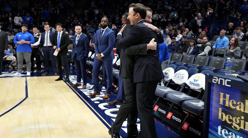 Xavier head coach Richard Pitino, right. wearing a full suit like his father, Rick Pitino, left, embraces him before a college basketball game St. John's, Saturday, Jan. 24, 2026, in Cincinnati. (AP Photo/Kareem Elgazzar)