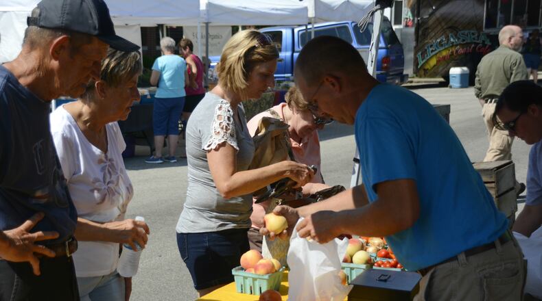 Market-goers at the Village Green Farmers Market in Fairfield buy produce at Johnson Family Farm’s booth. The city of Fairfield is looking to bring Hanover Winery to its farmers’ market, which re-opens later this spring. MICHAEL D. PITMAN/STAFF