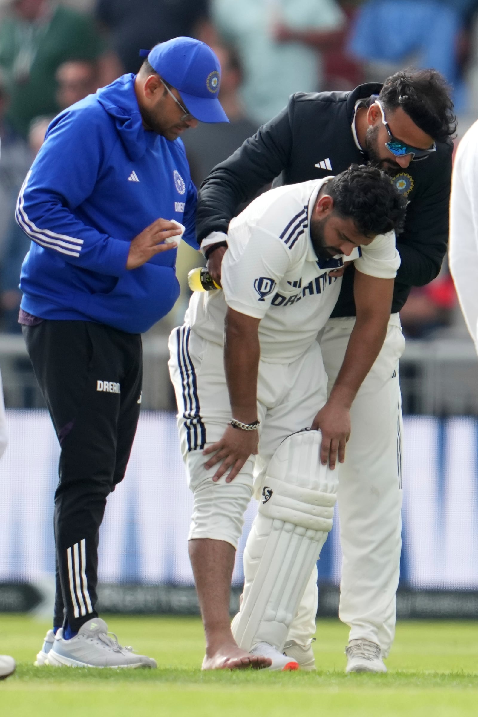 India's Rishabh Pant, center, assisted by team physiotherapist and teammate after he is getting hurt during the fourth cricket test match between England and India at Emirates Old Trafford, Manchester, England, Wednesday, July 23, 2025.(AP Photo/Jon Super)
