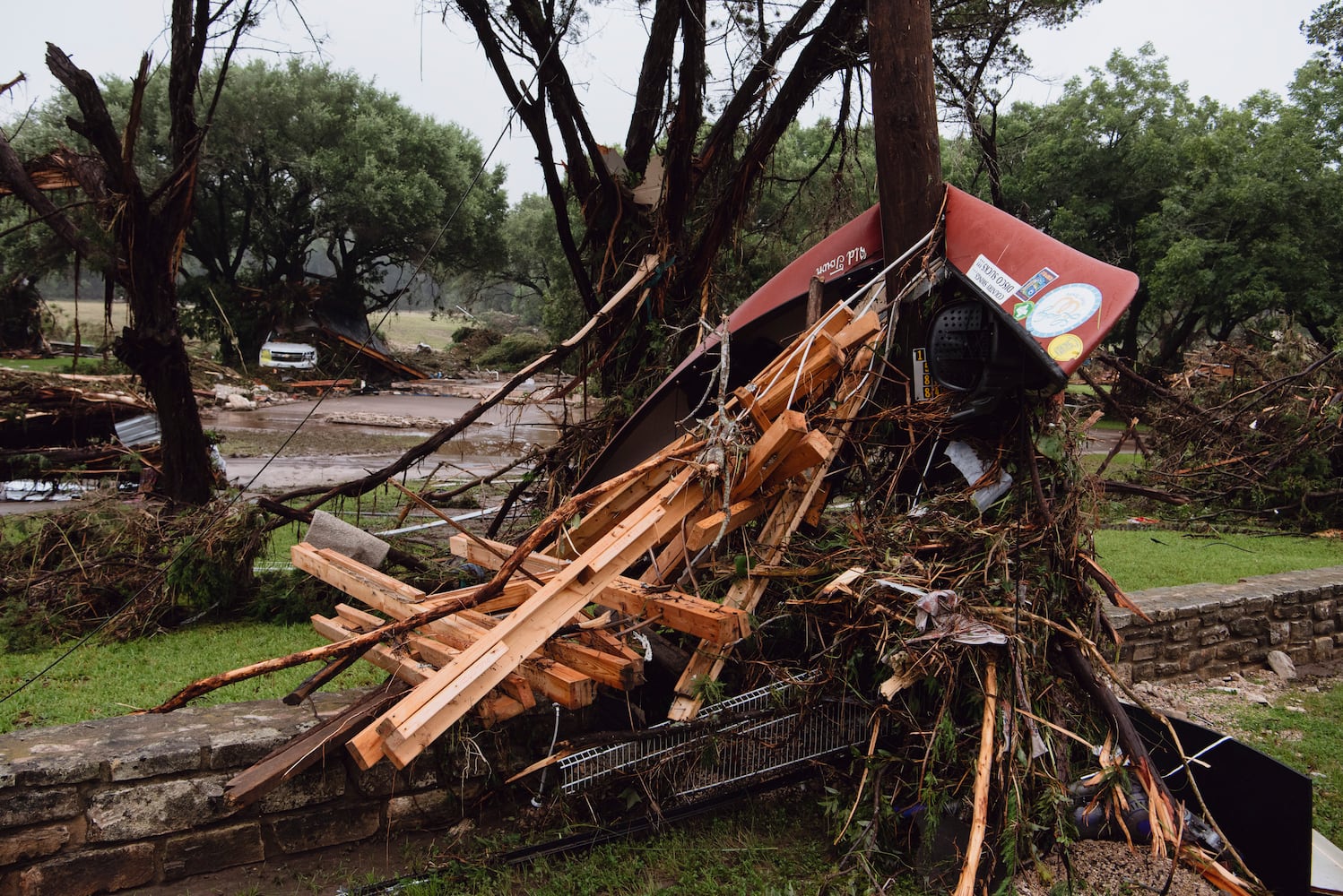 Debris, including a canoe, wrapped around a tree by floodwaters on the road to Camp Mystic in Hunt, Texas, on Saturday, July 5, 2025. (Carter Johnston/The New York Times)