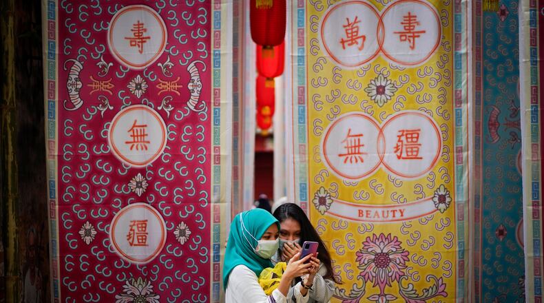 FILE - Two Malay girls check a mobile phone at a fabric installation decoration at Kwai Chai Hong, the Chinatown area in downtown Kuala Lumpur, Malaysia, Tuesday, March 30, 2021. (AP Photo/Vincent Thian, File)