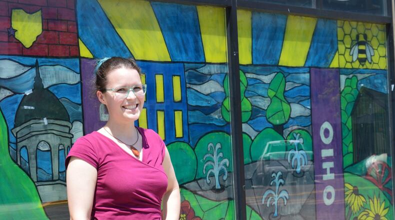Alyse Capaccio stands in front of the Uptown window she painted as part of the Enjoy Oxford mural project in which artists were invited to paint windows of vacant business locations. CONTRIBUTED/BOB RATTERMAN