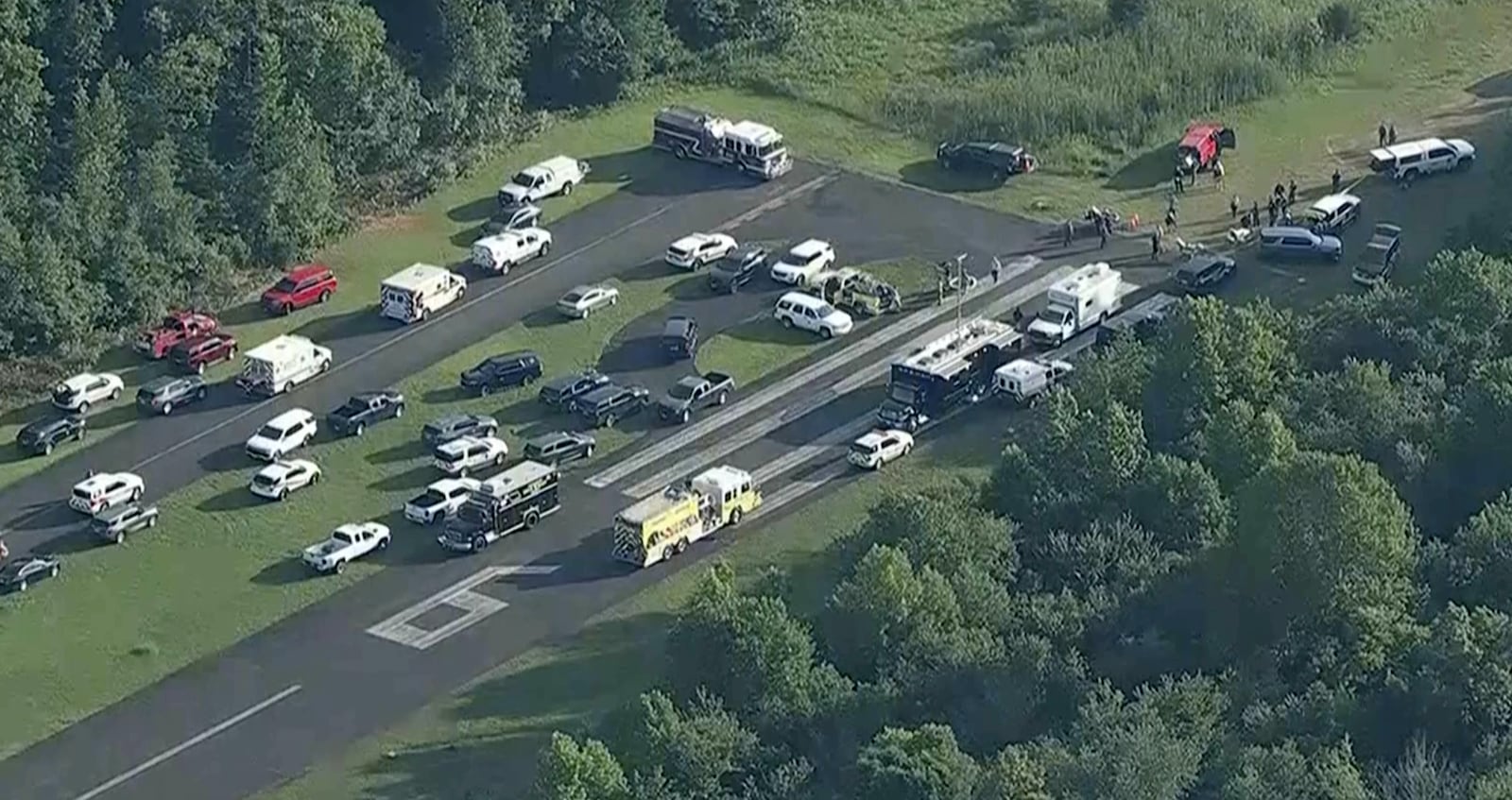This image taken from video provided by WPVI-TV/6ABC shows emergency personnel working at the scene where a small skydiving aircraft went off the end of a runway and crashed in the woods at Cross Keys Airport in Gloucester County, N.J., Wednesday, July 2, 2025. (WPVI-TV/6ABC via AP)