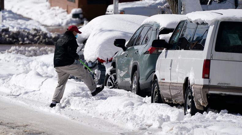 A motorist tries to clear snow to drive his van after a powerful late winter storm dumped more than 2 feet of snow Monday, March 15, 2021, in Denver. The storm shut down major roadways, canceled school and closed the state legislature. (AP Photo/David Zalubowski)