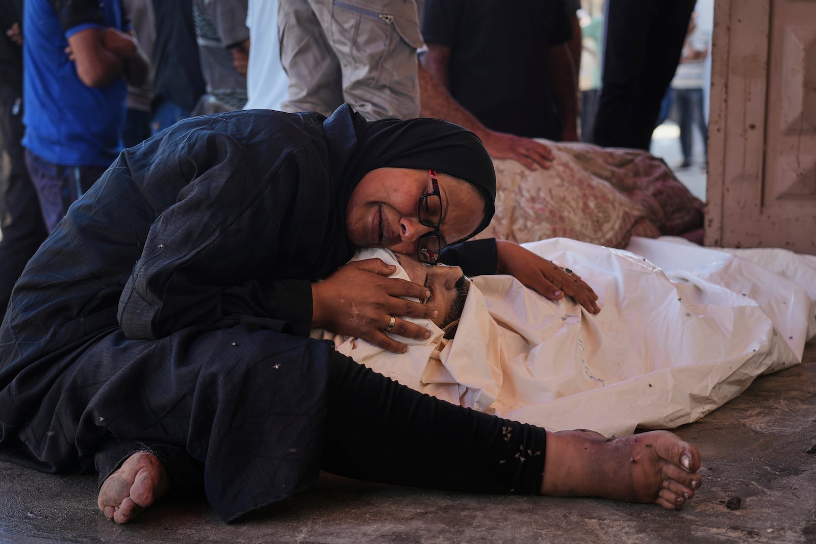 Khaleda El-Feki embraces the body of her husband, Mohamed El-Maghribi, who was killed in an Israeli airstrike, at Al-Aqsa Hospital in Deir al-Balah, central Gaza Strip, Thursday, July 24, 2025. (AP Photo/Abdel Kareem Hana)