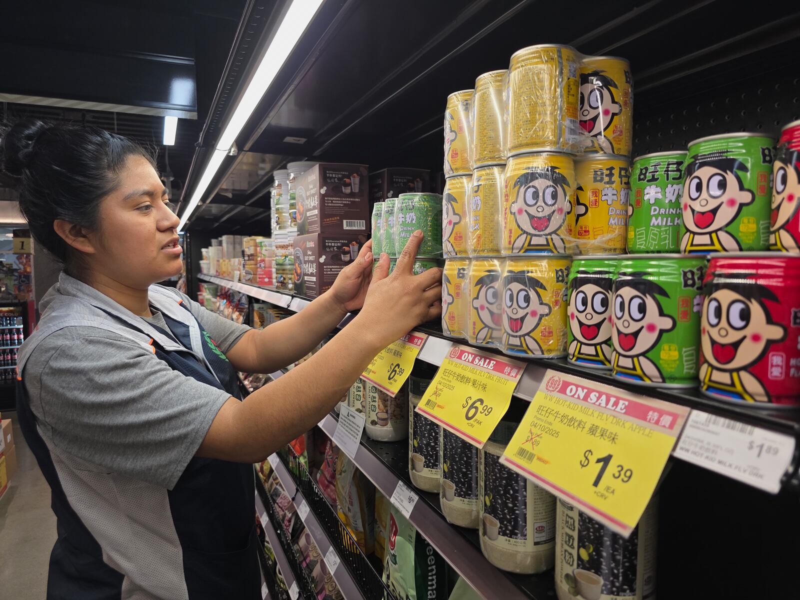 Maria Anselmo stacks Chinese imported canned Hot-Kid milk beverages in an aisle at 99 Ranch Market, an Asian grocery store in Los Angeles Monday, April 7, 2025. (AP Photo/Damian Dovarganes)