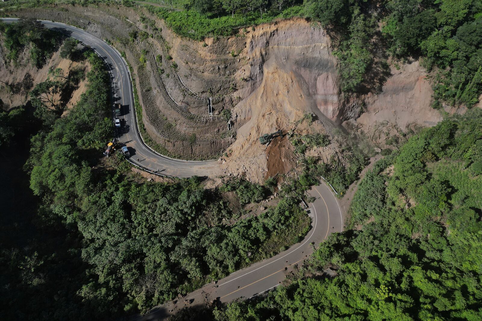 A backhoe works to clear a road blocked by a landslide in Palin, Guatemala, after dozens of earthquakes and aftershocks were recorded in a matter of hours. (AP Photo/Moises Castillo)
