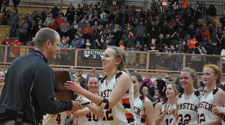 Minster senior forward Jessica Falk (right) accepts the Division IV regional championship trophy on behalf of her team from Butler athletic director Jordan Shumaker following the Wildcats’ win against Fort Loramie in the final, March 9, 2019. Nick Dudukovich/CONTRIBUTED