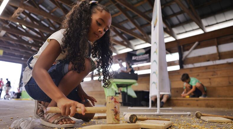 Sofia Snell, 6, cracks corn as she learns about agriculture during Farmertown at the Butler County Fair Thursday, July 25, 2024 in Hamilton. NICK GRAHAM/STAFF
