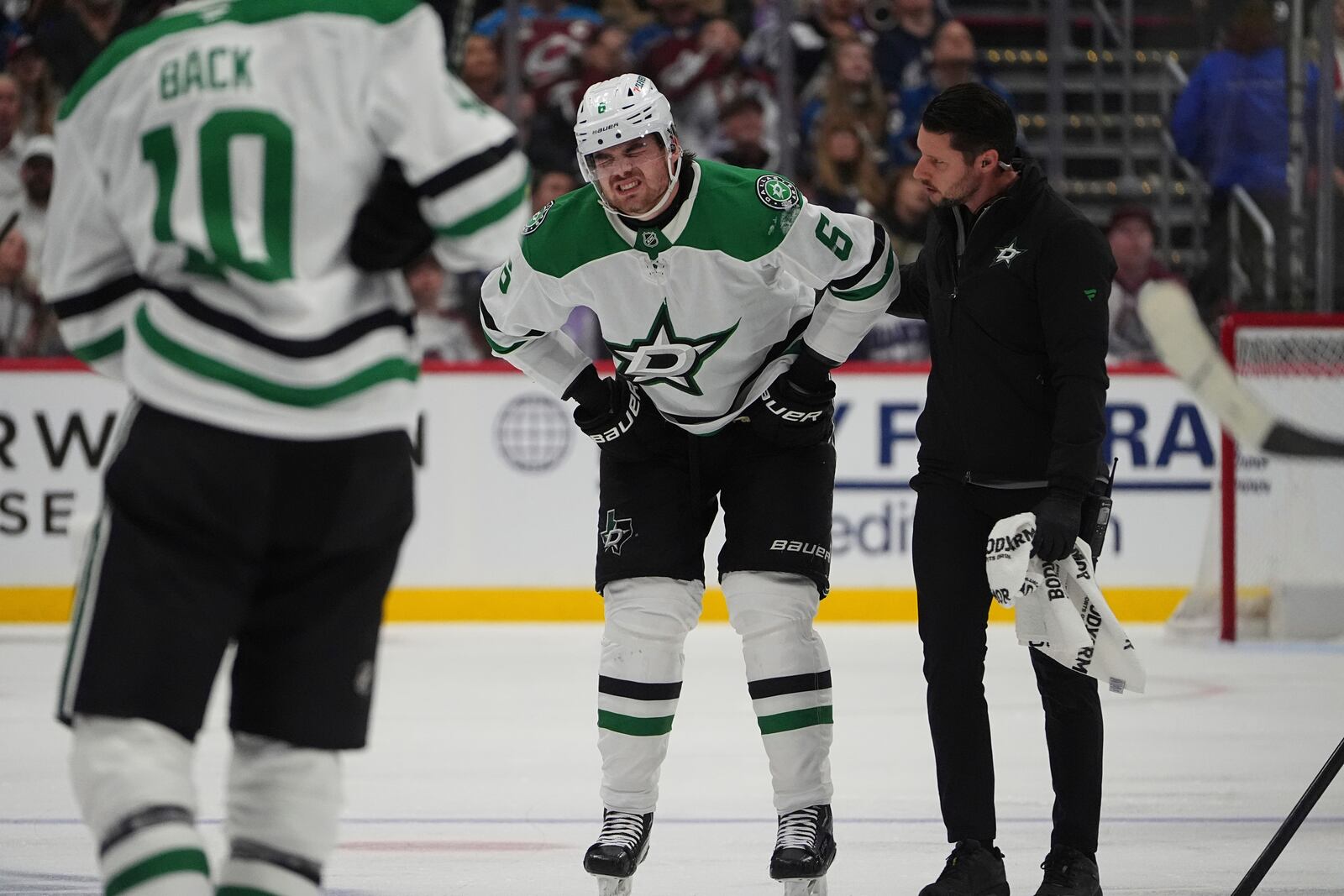 Dallas Stars defenseman Lian Bichsel, center, is helped to the team box after being injured in the second period of Game 3 of an NHL hockey first-round playoff series against the Colorado Avalanche Wednesday, April 23, 2025, in Denver. (AP Photo/David Zalubowski)