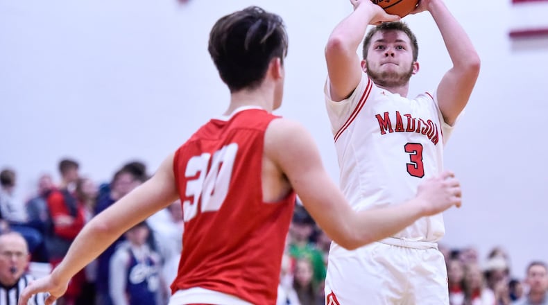 Madison’s Mason Whiteman puts up a shot over Carlisle’s Austin Redavide during Friday night’s game in Madison Tonwship. Madison won 71-45. NICK GRAHAM/STAFF