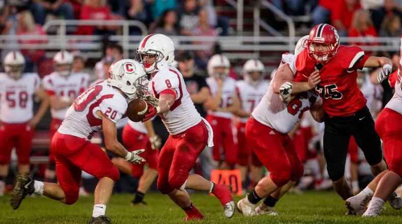 Carlisle’s Dane Flatter (8) hands off to Ryan Neal (20) as Madison’s Levi McMonigle (35) breaks through the line Friday night at Brandenburg Field in Madison Township. The host Mohawks won 54-0. NICK GRAHAM/STAFF