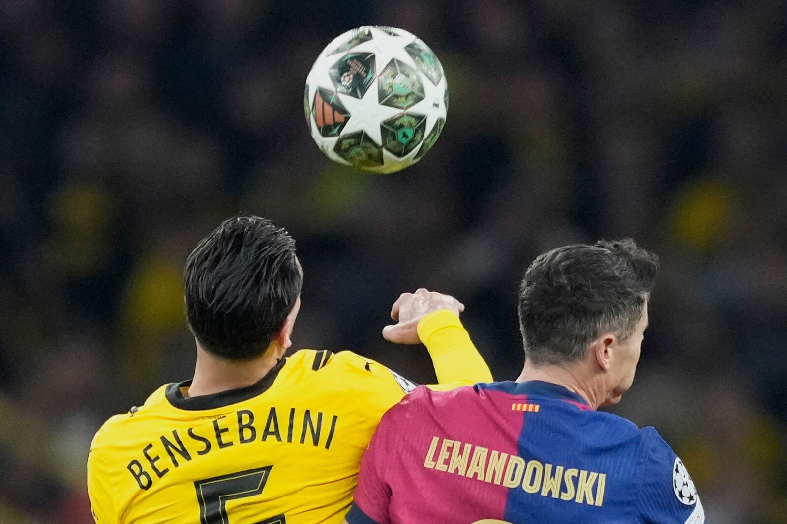 Dortmund's Ramy Bensebaini, left, duels for the ball with Barcelona's Robert Lewandowski during the Champions League quarterfinals second leg soccer match between Borussia Dortmund and Barcelona, at the Signa-Iduna Park in Dortmund, Germany, Tuesday, April 15, 2025. (AP Photo/Martin Meissner)
