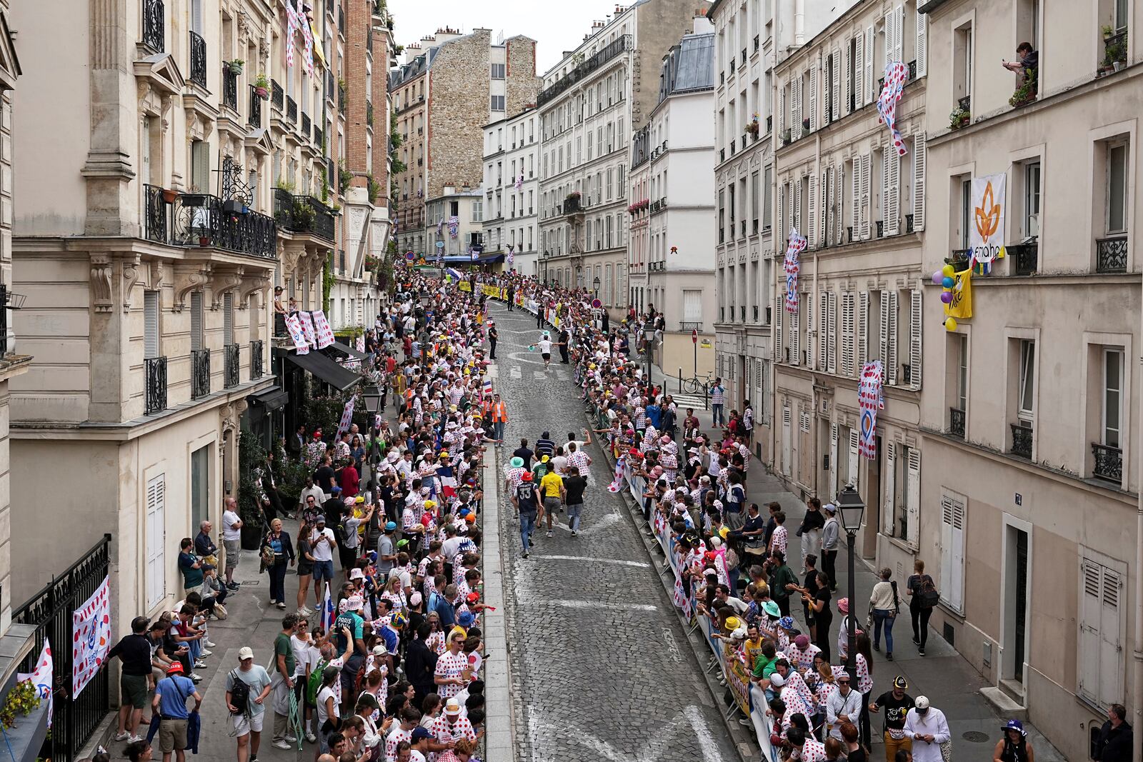 Cycling fans run on the street in the Montmartre district before the last stage of the Tour de France cycling race between Mantes-la-Ville and Paris, Sunday, July 27, 2025 in Paris (AP Photo/Laurent Cipriani)