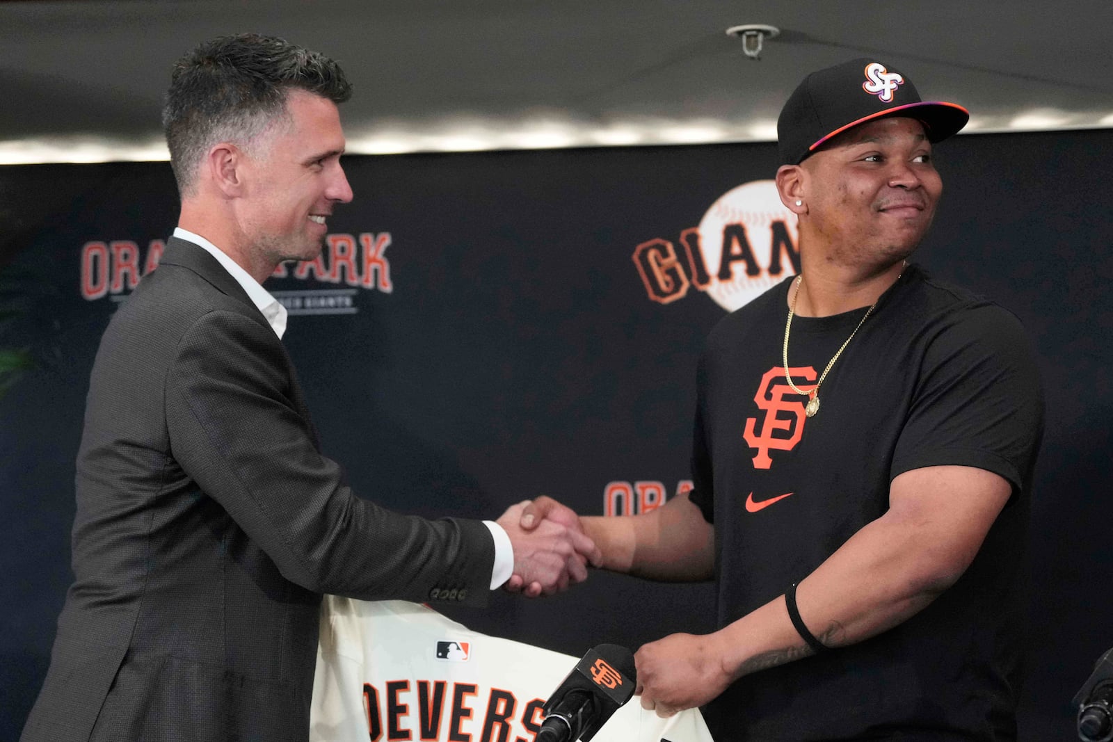 San Francisco Giants President of Baseball Operations Buster Posey, left, shakes hands with Rafael Devers during a news conference before a baseball game between the Giants and the Cleveland Guardians in San Francisco, Tuesday, June 17, 2025. (AP Photo/Jeff Chiu)