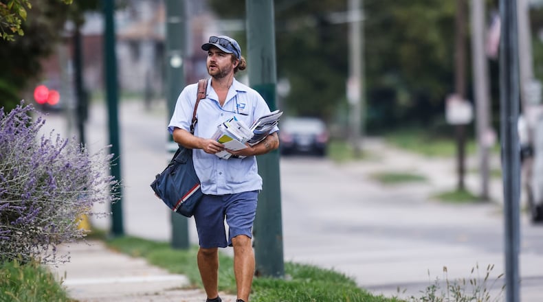 A mail carrier delivers mail on Watervliet Ave. Monday Oct. 4, 2021. The mail may soon cost more and take long to arrive under postmasters 10-year plan. JIM NOELKER/STAFF