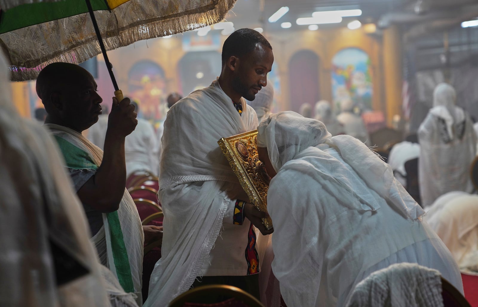 Worshippers kiss the holy Gospel during service at Re'ese Adbarat Debre Selam Kidist Mariam Church, an Ethiopian Orthodox Tewahedo church, in Washington, D.C., Saturday, April 5, 2025. (AP Photo/Jessie Wardarski)