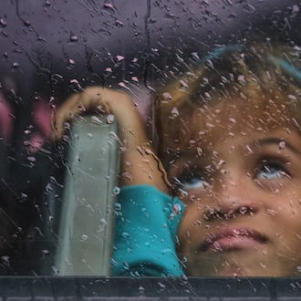 A girl looks out a rain-splattered bus window as she is evacuated before the arrival of Hurricane Melissa in Canizo, a community in Santiago de Cuba, Tuesday, Oct. 28, 2025. (AP Photo/Ramón Espinosa)