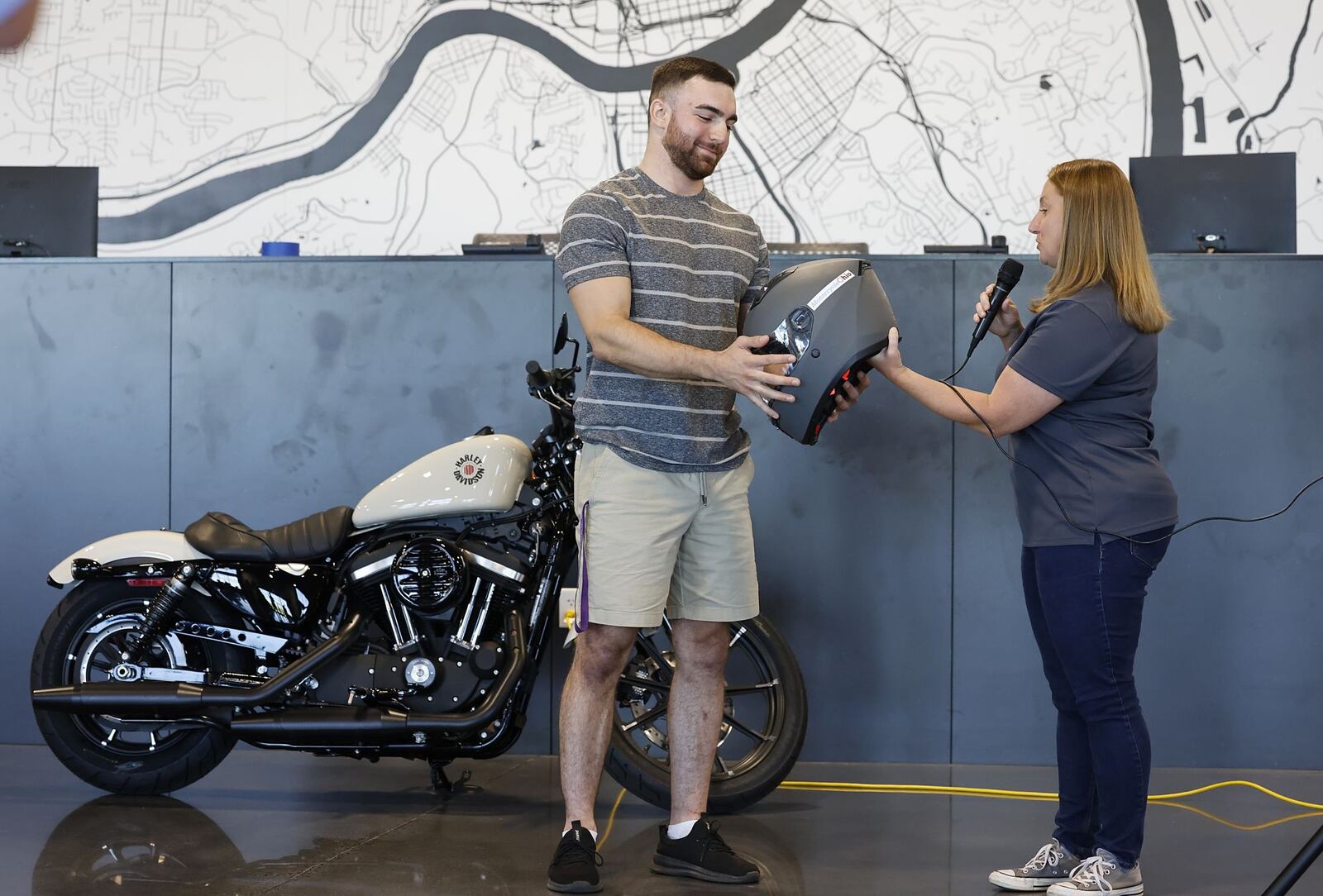 Michele Piko, right, state program coordinator with Motorcycle Ohio, a division of the Ohio Traffic Safety Office, presented Ricky McVety III, of Middletown, a “Saved by the Helmet” award Wednesday, 
Aug. 31, 2022 at Queen City Harley-Davidson in West ChesterTownship. The award is given throughout the year to those who survive serious crashes while wearing a helmet. On October 12,  2021, McVety was hit by an oncoming driver in a minivan who pulled in front of him at the intersection of Breiel Blvd. and Central Ave. in Middletown. McVety was hospitalized with serious injuries, but believes his helmet saved his life. NICK GRAHAM/STAFF