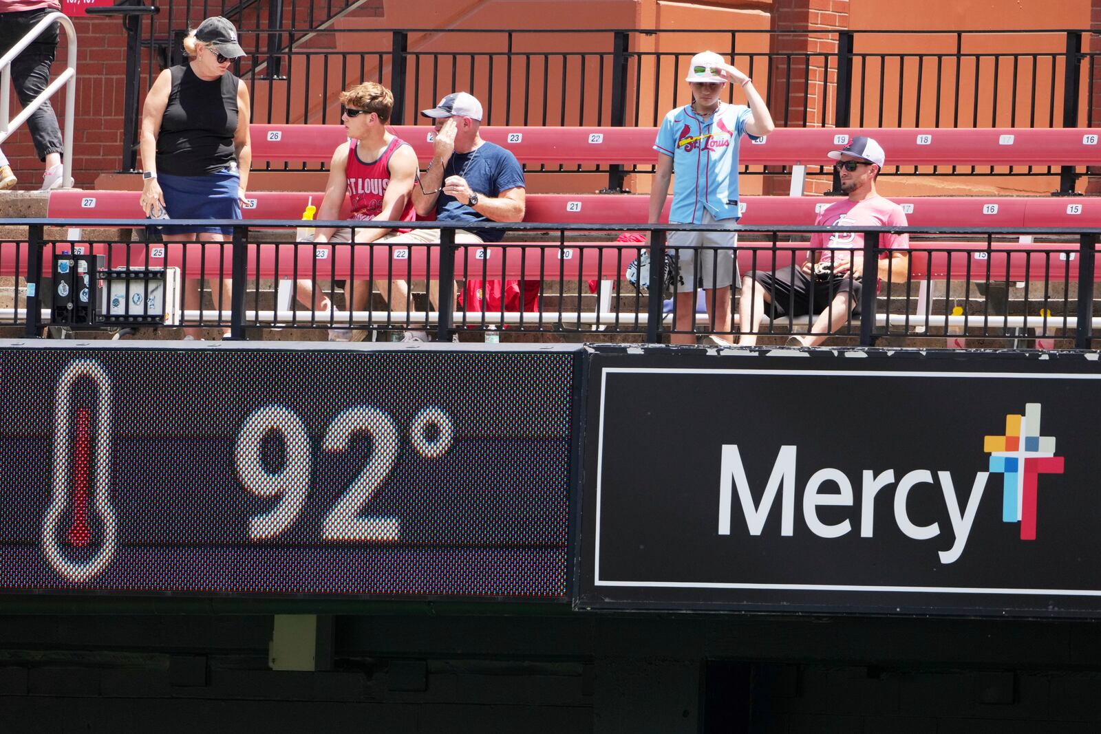 Fans in the bleachers try to stay cool in Busch Stadium before the start of a baseball game between the St. Louis Cardinals and the Cincinnati Reds Saturday, June 21, 2025, in St. Louis. (AP Photo/Jeff Roberson)