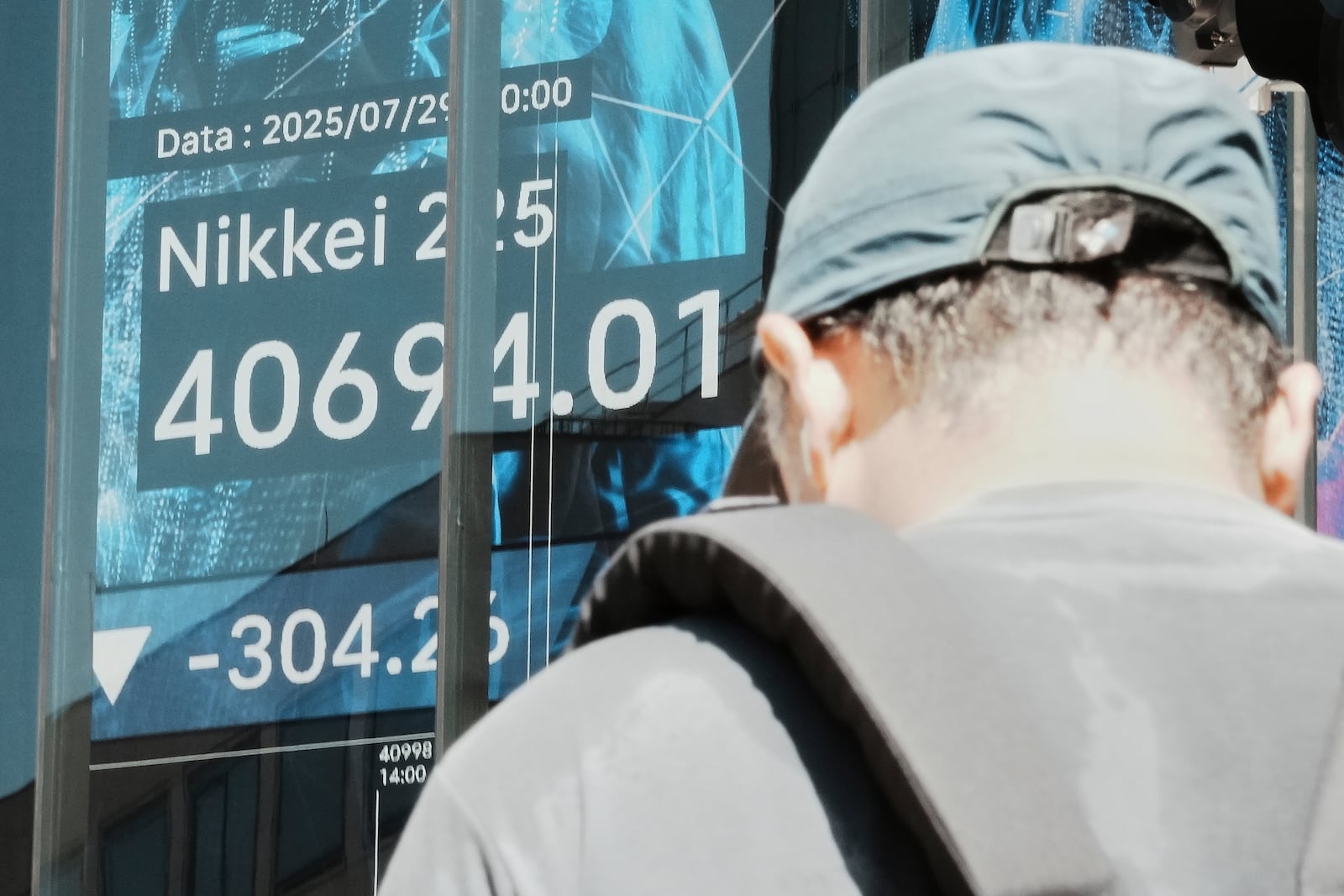 A person stands in front of an electronic stock board showing Japan's Nikkei index at a securities firm Tuesday, July 29, 2025, in Tokyo. (AP Photo/Eugene Hoshiko)