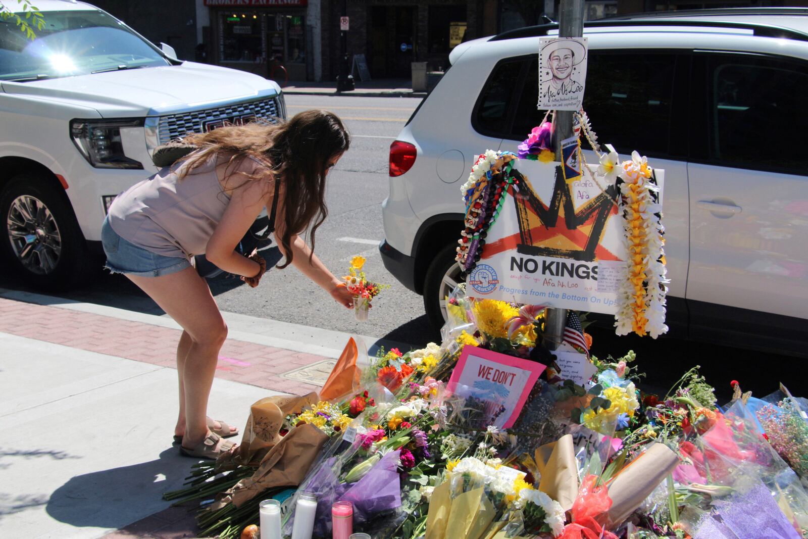 A woman lays flowers Tuesday, June 17, 2025, at a makeshift memorial for Arthur Folasa Ah Loo, known to friends and family as Afa, on the city block in Salt Lake City, Utah, where Ah Loo was fatally shot during a "No Kings" protest on Saturday, June 14. (AP Photo/Hannah Schoenbaum)