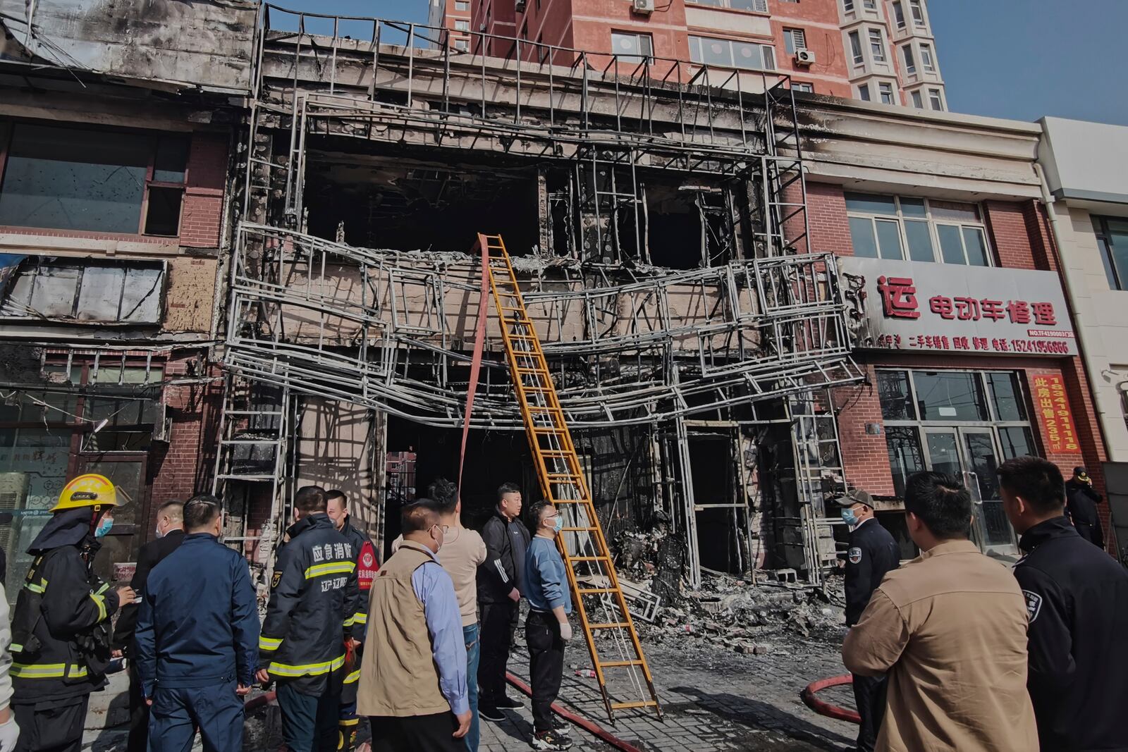 In this photo released by Xinhua News Agency, firefighters and officials survey the site of a restaurant fire in Liaoyang, northeastern China's Liaoning province on Tuesday, April 29, 2025. (Xinhua via AP)