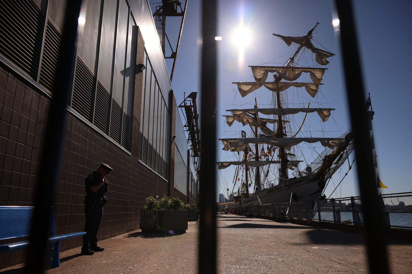 A New York Police officer stands watch on Pier 35 where the Cuauhtémoc, a masted Mexican Navy training ship that collided with the Brooklyn Bridge the night before, sits docked. (AP Photo/Yuki Iwamura)