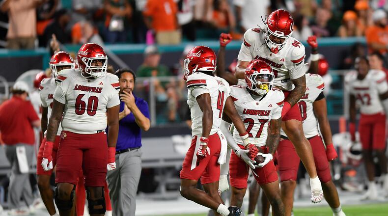 Louisville defensive back Jojo Evans Jr. (27) celebrates after intercepting a pass with defensive lineman Jordan Guerad (99) during the second half of an NCAA college football game against Miami, Friday, Oct. 17, 2025, in Miami Gardens, Fla. (AP Photo/Michael Laughlin)