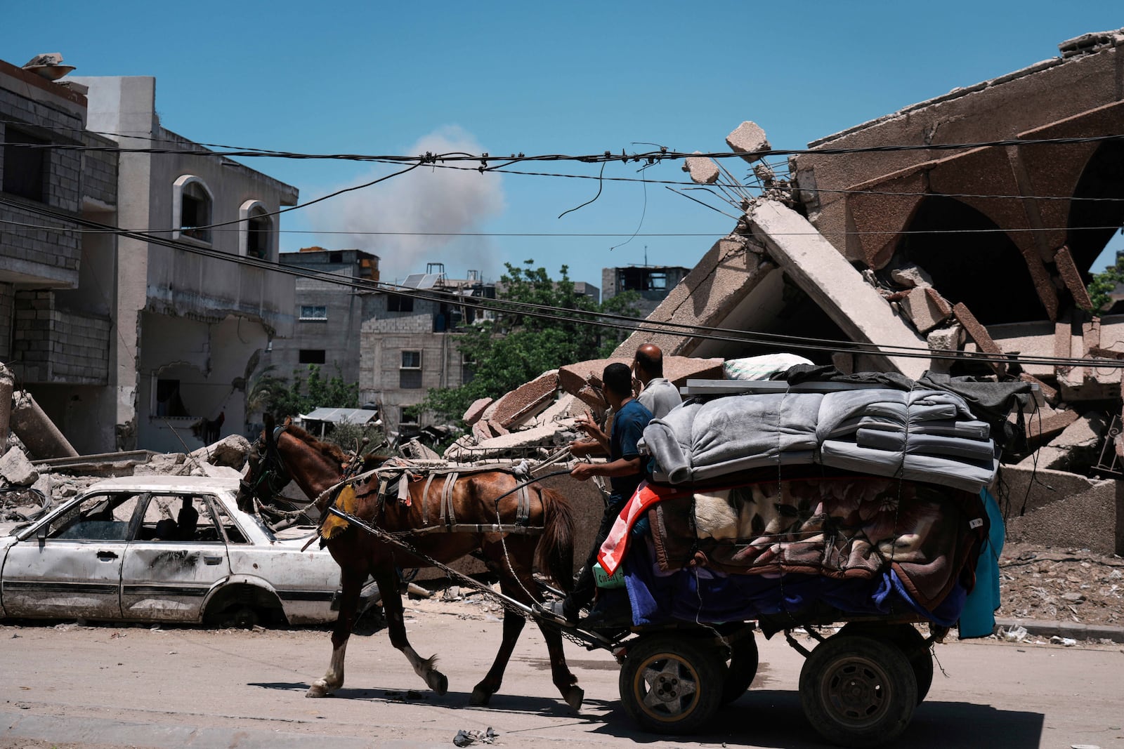 Smoke rises to the sky following an Israeli airstrike as Palestinians fleeing Jabalia move with their belongings in Gaza City, Friday, May 30, 2025. (AP Photo/Jehad Alshrafi)