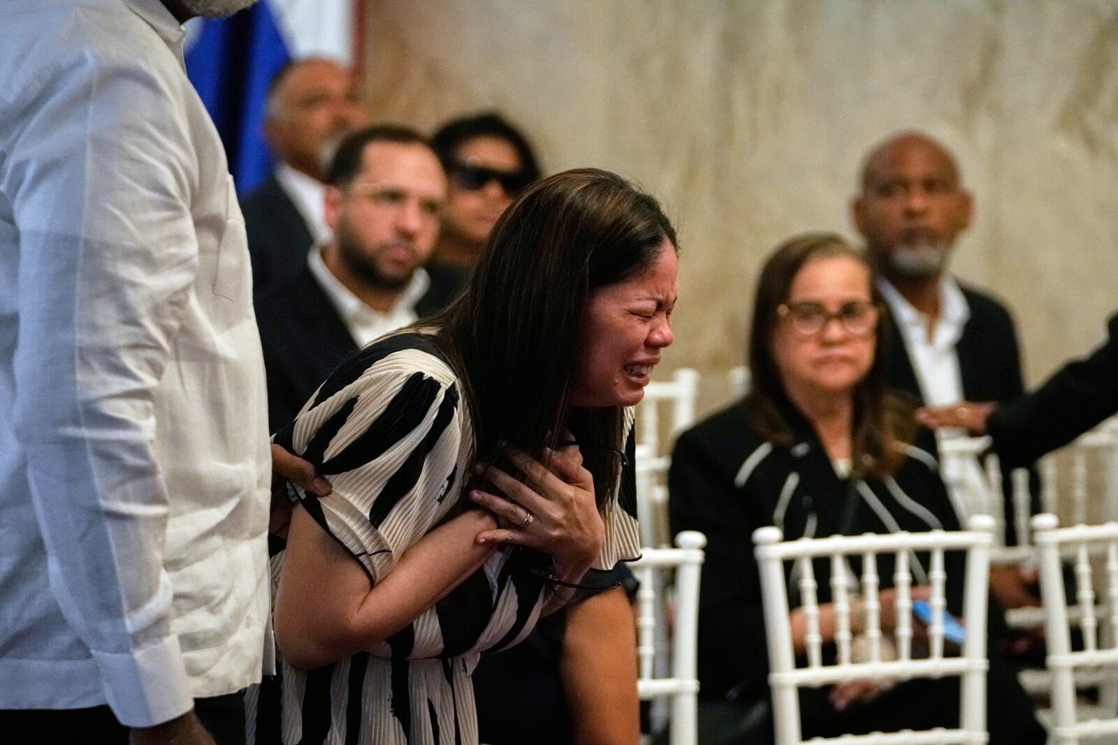 Zulinka, center, the daughter of Dominican singer Rubby Perez who died in the roof collapse at the Jet Set nightclub during his merengue concert, cries during his wake at the Eduardo Brito National Theater in Santo Domingo, Dominican Republic, Thursday, April 10, 2025. (AP Photo/Matias Delacroix)
