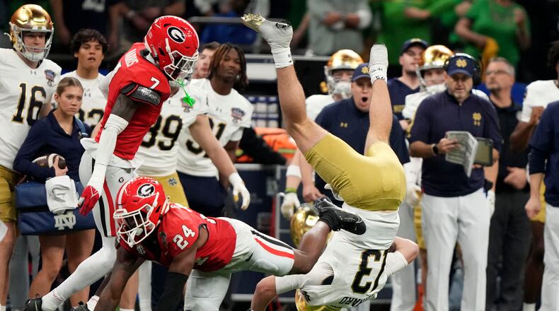Notre Dame quarterback Riley Leonard (13) is tackled by Georgia defensive back Malaki Starks (24) and defensive back Daniel Harris (7) after running for a first down during the second half in the quarterfinals of a College Football Playoff, Thursday, Jan. 2, 2025, in New Orleans. (AP Photo/Gerald Herbert)